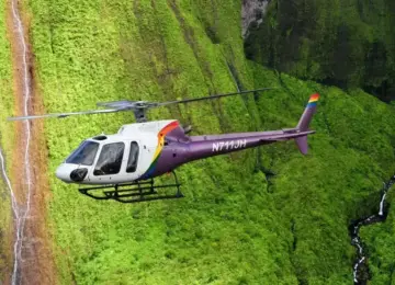 helicopter flying over green cliffs with narrow waterfalls in Hawaii