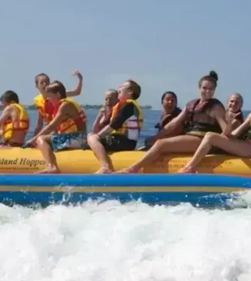 group of people riding a yellow banana boat in the ocean with life jackets