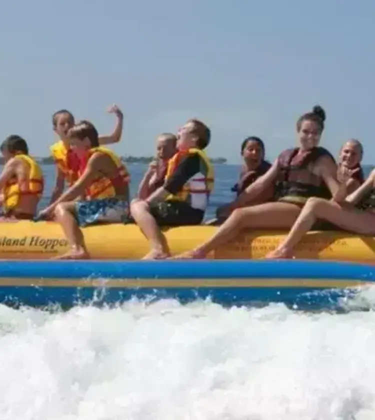 group of people riding a yellow banana boat in the ocean with life jackets