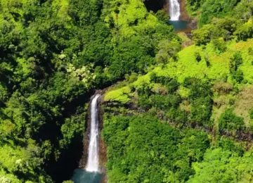 Three cascading waterfalls amid dense green Hawaiian forest
