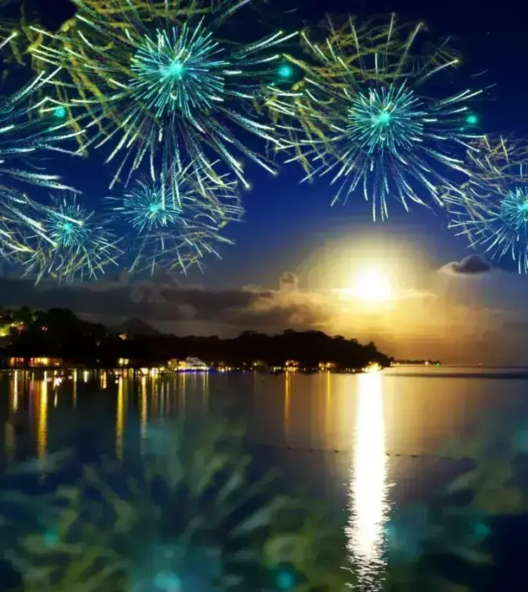 Nighttime fireworks over a calm coastal scene reflecting lights on water