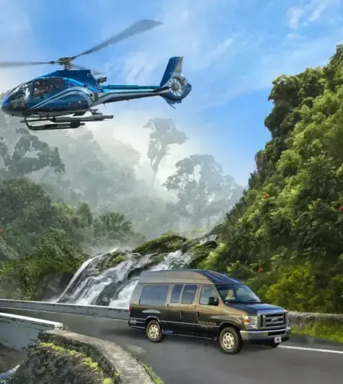 Blue helicopter flying over lush green mountains and a tour van driving on a curved bridge near a waterfall