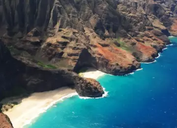 Rocky Na Pali Coast cliffs with blue ocean and sandy beach