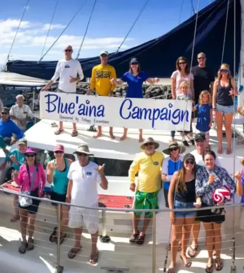 diverse group of people on a boat holding a Blue aina Campaign banner with ocean background