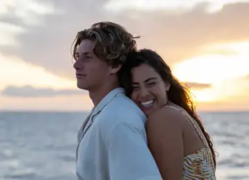 Couple embracing and smiling by the ocean during sunset