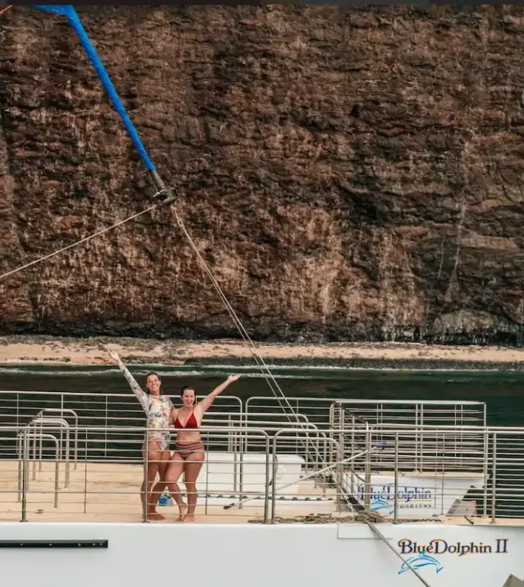 people on Blue Dolphin II boat with rocky cliff in background