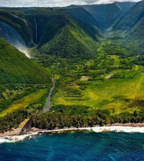 lush green Hawaiian valley with coastline, river, and waterfall