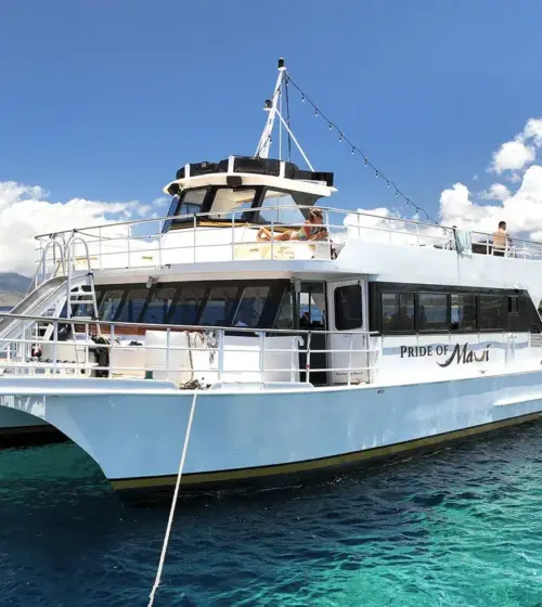 catamaran boat Pride of Maui on clear blue ocean with island and sunny sky background