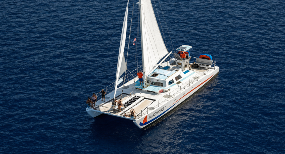 white sailboat named Seasworks with passengers sailing on dark blue ocean