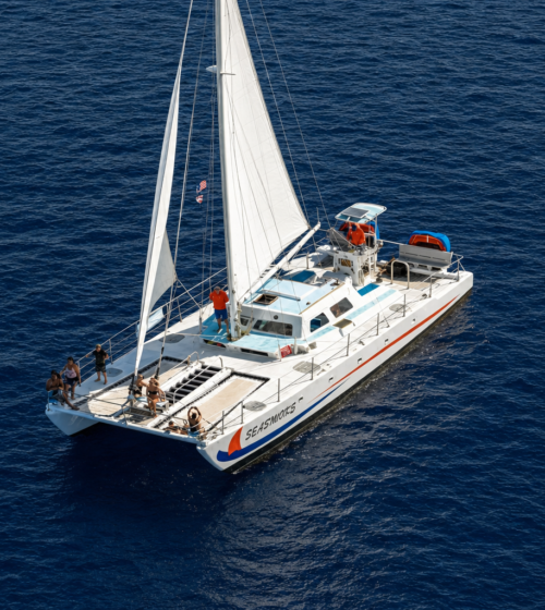 white sailboat named Seasworks with passengers sailing on dark blue ocean