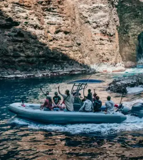 boat with people cruising inside a rocky sea cave with water trail