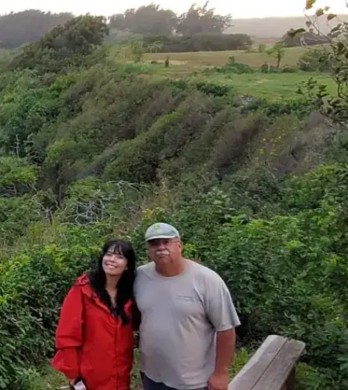 Couple standing beside green mountain ridge with mist in background