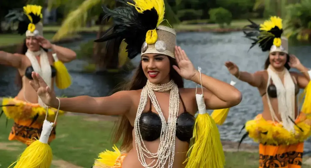 Hawaiian dancers dressed in traditional attire performing a dance near water