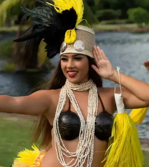 Hawaiian dancers dressed in traditional attire performing a dance near water