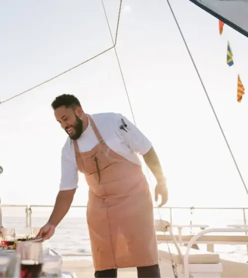 Chef serving food to happy guests on a yacht during sunset