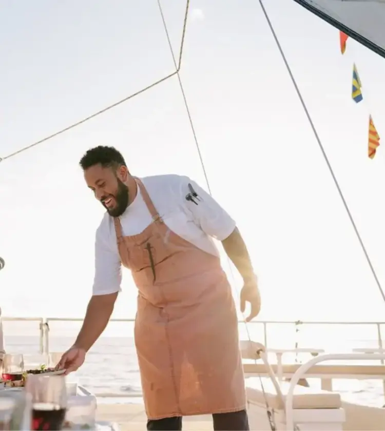 Chef serving food to happy guests on a yacht during sunset