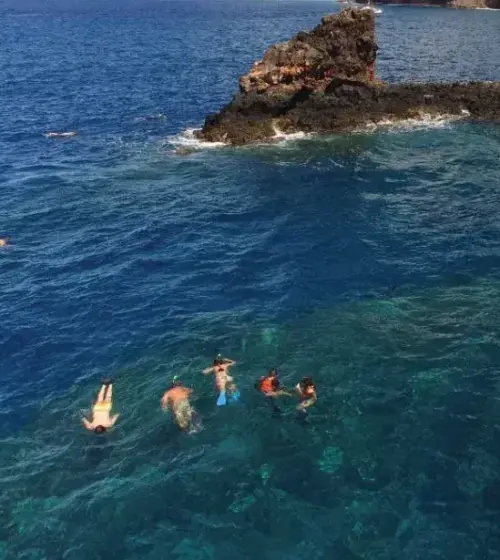 snorkelers swimming near rock formation in clear ocean water around Maui Hawaii