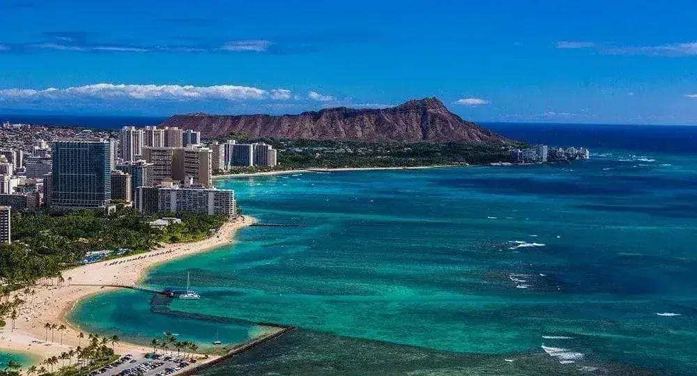 Panoramic view of Honolulu beach and city skyline with Diamond Head volcano in the background under blue sky