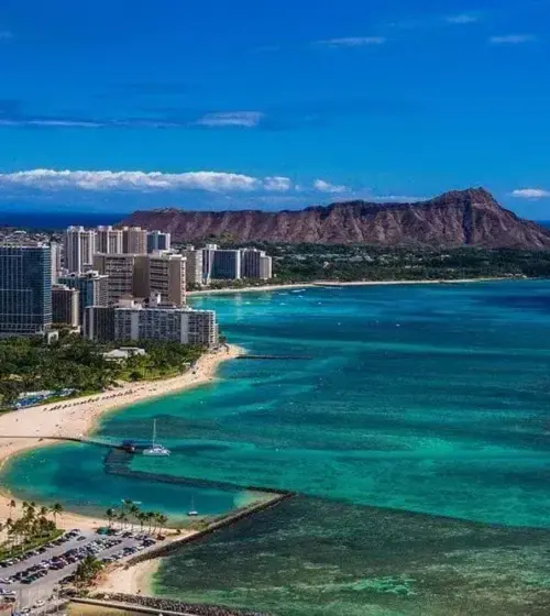 Panoramic view of Honolulu beach and city skyline with Diamond Head volcano in the background under blue sky