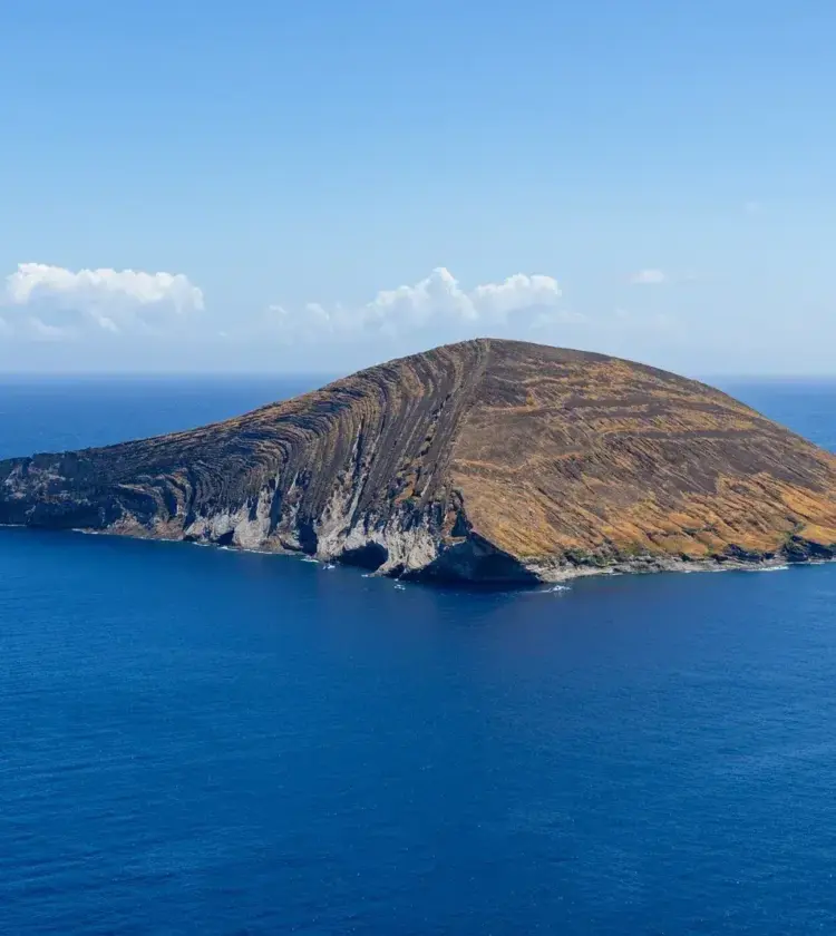 volcanic island surrounded by deep blue ocean under clear sky