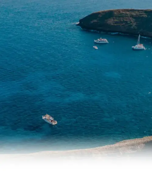 boats anchored in a curved bay with a rocky coastline