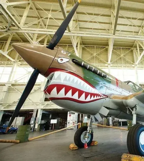 Historic World War II fighter plane with shark mouth paint in large hangar