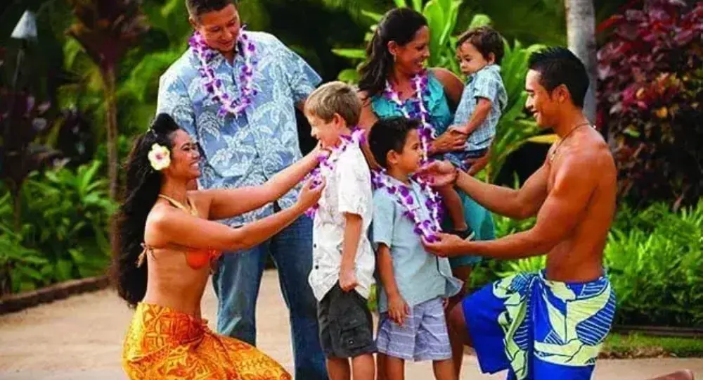 Hawaiian family greeting children with leis in tropical garden