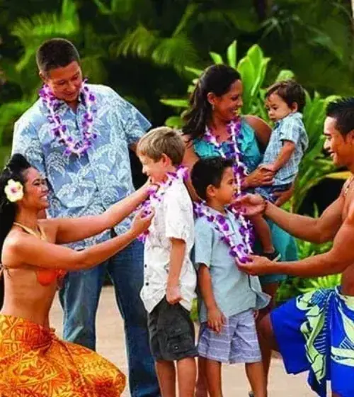 Hawaiian family greeting children with leis in tropical garden